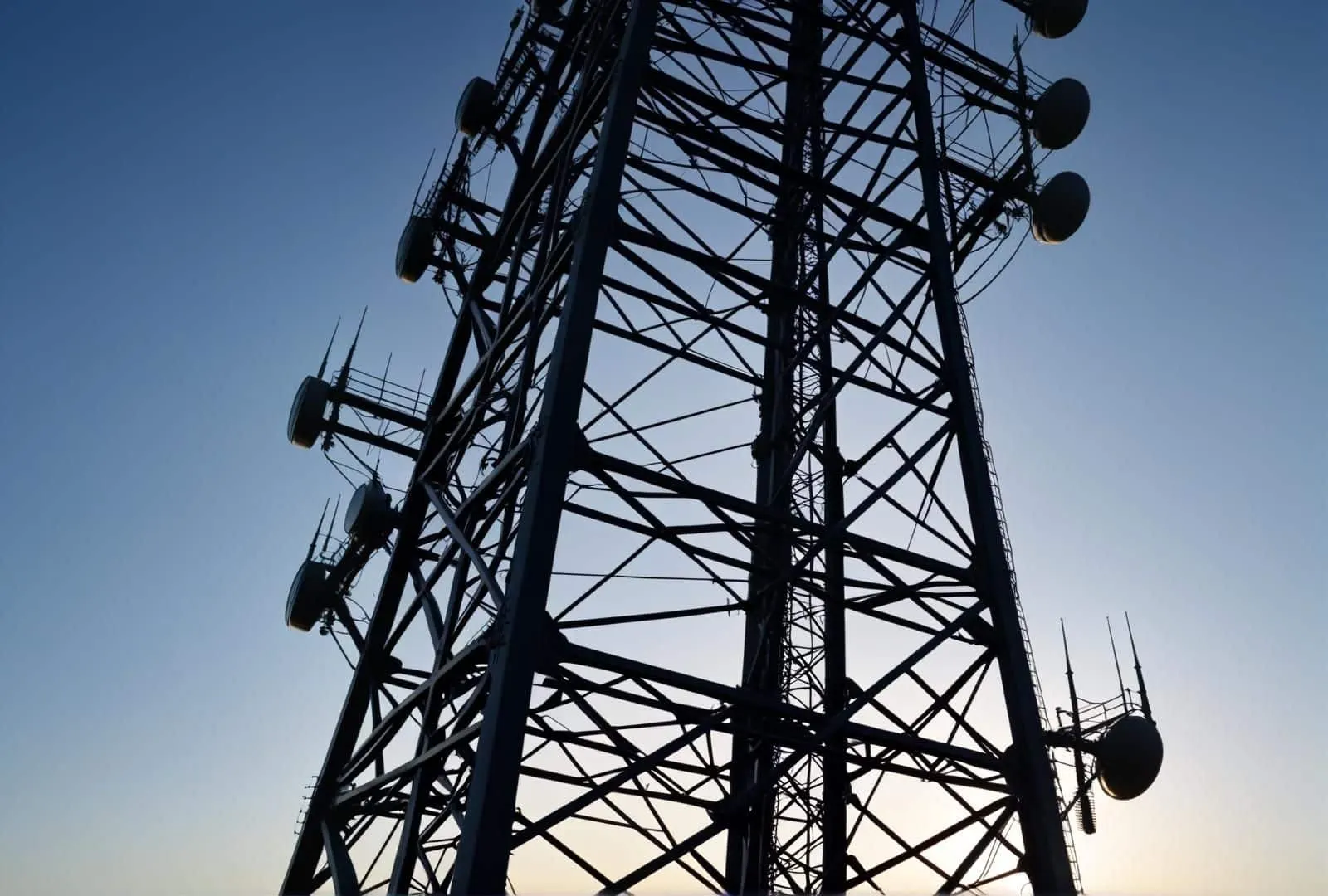 Cellular tower with antennas against a dusk sky