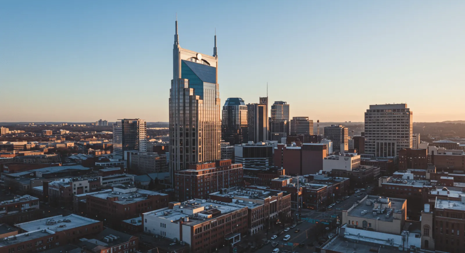 Downtown Nashville skyline at sunset, led by a tall tower with two spires